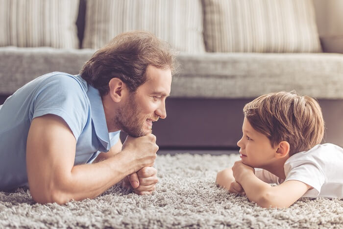 Pai e filho conversando deitados no tapete